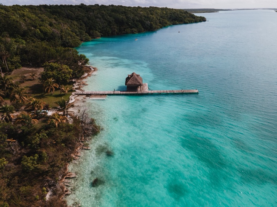 Aerial view of a jetty and thatched hut on a turquoise lagoon
